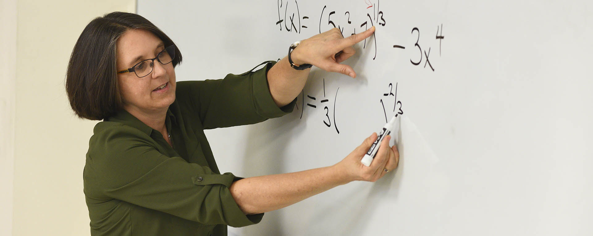 Math professor demonstrating a math problem on the board.